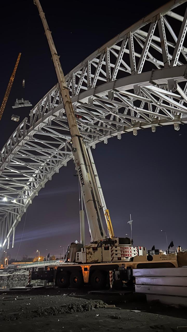 Steel arch bridge erection at night — Steel Power Co.